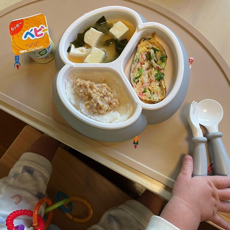 A child's meal with rice and minced meat, tofu soup, and an omelet in a divided dish, with a yogurt drink and utensils on a tray.